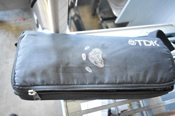 TDK-branded black zippered case with a white logo and design, containing cassette tapes. Zipper and fabric in used condition.