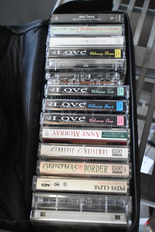 Assorted cassette tapes in a black carrying case, featuring artists like Bee Gees and Anne Murray.