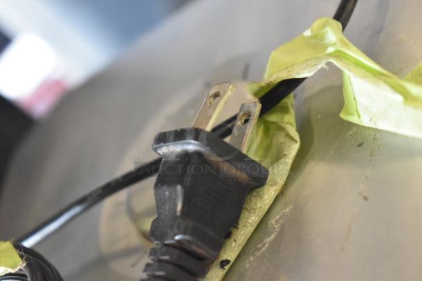 Close-up of a black power plug for a Zylux Multimedia Computer, positioned over green tape.