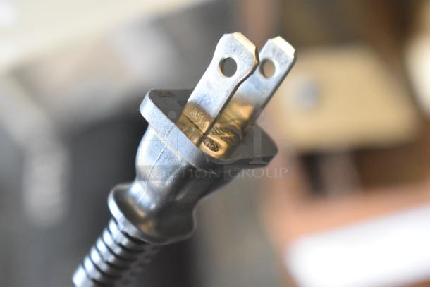 Close-up of a standard two-prong electrical plug with visible safety markings on the prongs.