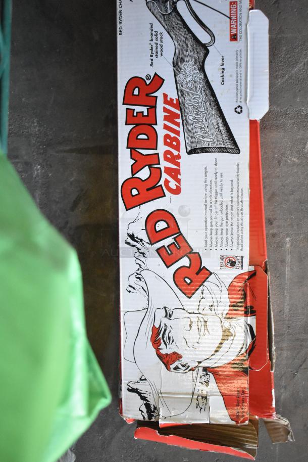 Red Ryder BB Gun box with bold red lettering and cowboy illustration, cardboard appears worn and open.