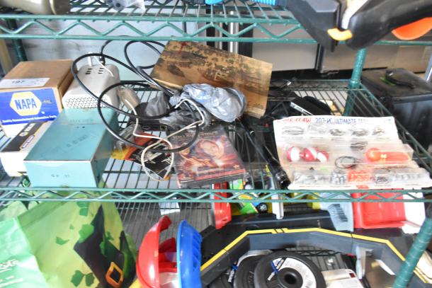 Two-tiered shelf holding fishing lures, windchimes, Nintendo Switch controller holder, boxes labeled "NAPA," and assorted items.