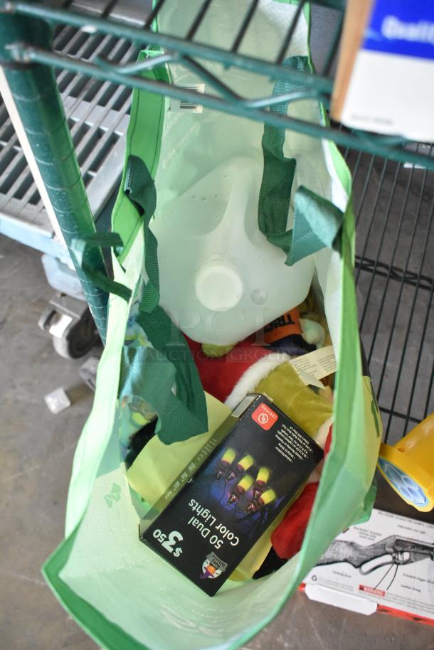 Green bag with various items including a box of color lights, a gallon jug, and assorted items. Auction lot with fishing lures, windchimes, Nintendo Switch controller holder.