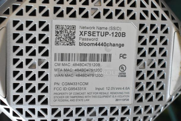 Label showing network name "XFSETUP-120B," password "bloom4440change," MAC addresses, and a Comcast property notice.