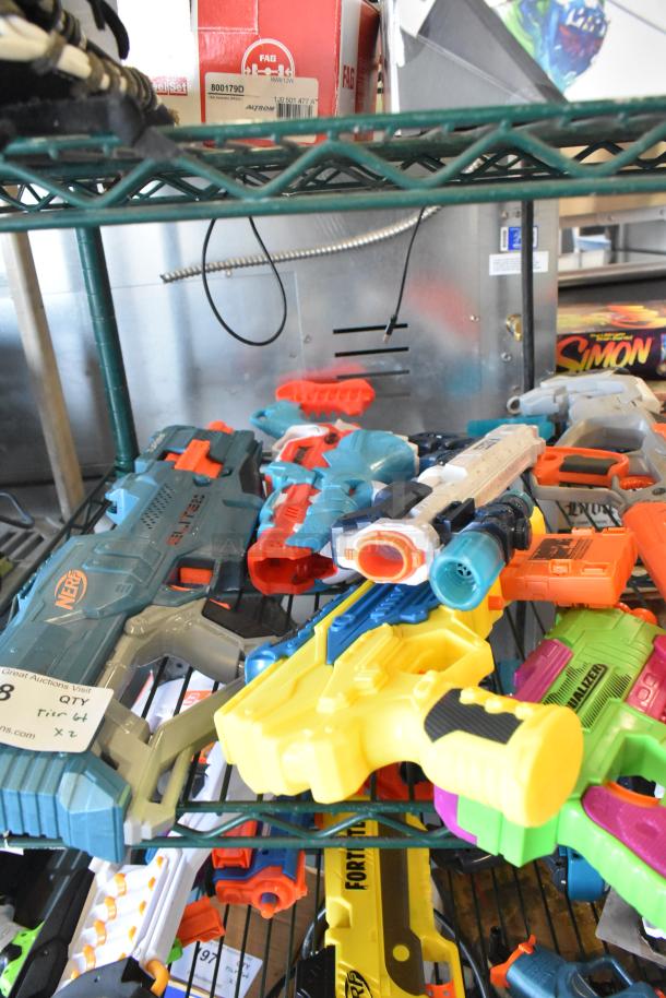 Two-tier lot of toy guns, including Nerf models, in various colors and designs. Visible tags indicate item quantity.