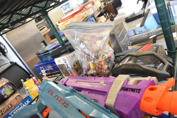 Two-tier lot with various items: Fortnite toy guns, Pop! figure box, bag of pens, board games, in good condition.