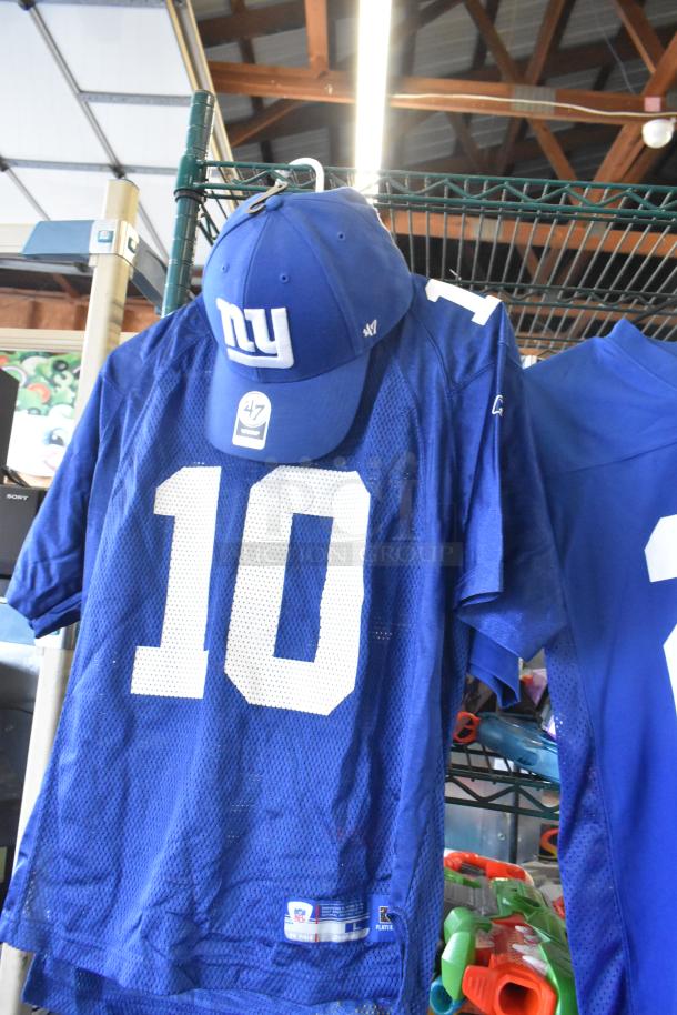 Two New York Giants jerseys on display with a matching cap, featuring player numbers and team logos. Visible Sony speaker in the background.