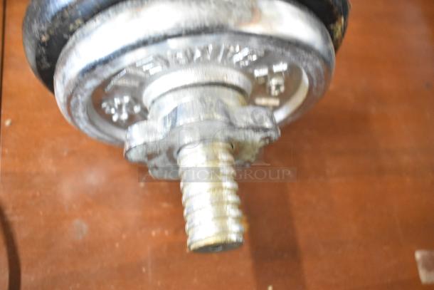 Close-up of a metal dumbbell with a threaded handle, secure spin lock, and visible weight markings. Slightly worn condition.