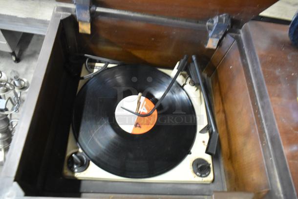 Victrola wood pattern counter with built-in record player, vintage design, visible wear, with rotary knobs and a record on the turntable.