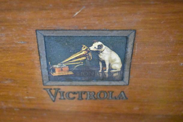Victrola wood pattern counter with record player, features a classic logo with a dog and phonograph, showcasing vintage charm.