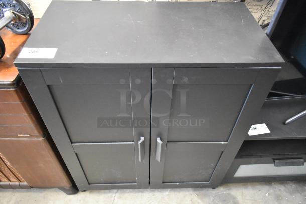 Black 2-door cabinet with sleek design, sturdy handles, and minor surface wear. Ideal for storage and organization.