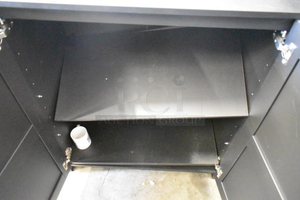 Black 2-door cabinet with interior shelves, minimal wear, and visible hinges. Ideal for storage, contemporary design.