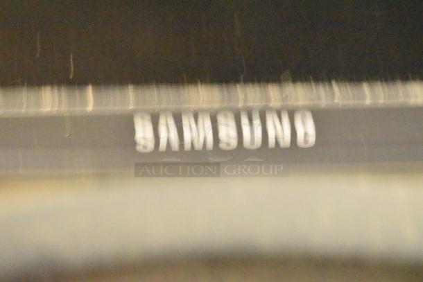 Samsung Television close-up; the image shows the blurry Samsung logo. Item includes TV stand. Buyer pickup required.