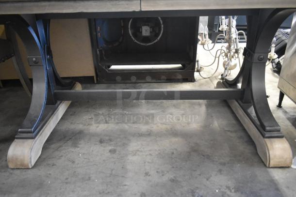 Wooden dining table leg detail with metal supports, rustic finish. No chairs visible. Suitable for six chairs.