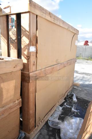 Brand new scratch and dent door, 144"x96", packaged in a wooden crate with protective markings and handling labels visible.