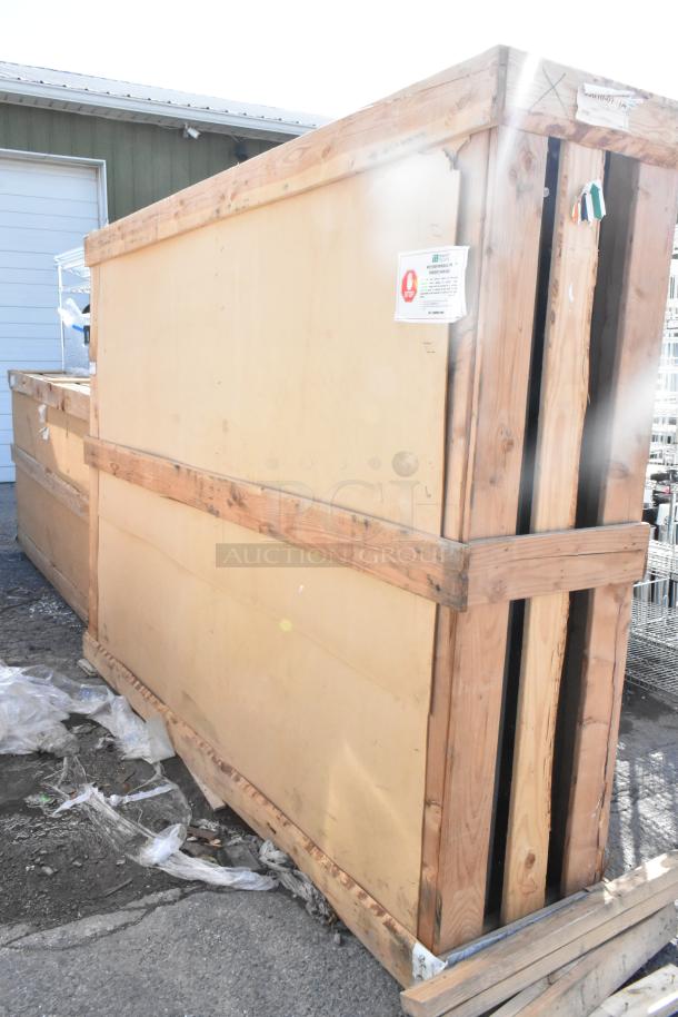 Brand new scratch and dent door, 144"x96", in wooden crate. Packaging shows minor wear and labels indicating handling instructions.