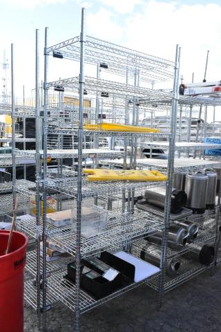 Chrome finish 6 tier wire shelving unit with contents, including wet floor caution signs. Buyer must dismantle.