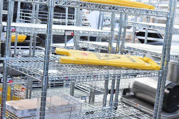 Chrome 6-tier wire shelving unit with contents, including yellow wet floor caution signs. Buyer must dismantle.