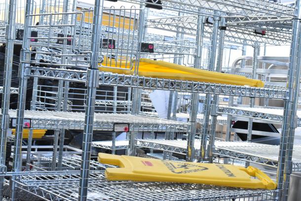 Chrome finish 6-tier wire shelving unit with yellow wet floor caution signs. Buyer must dismantle for shipping.