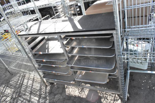 Metal cart with multiple metal baking pans on shelves, sturdy frame, wheels for mobility, suitable for kitchen use.