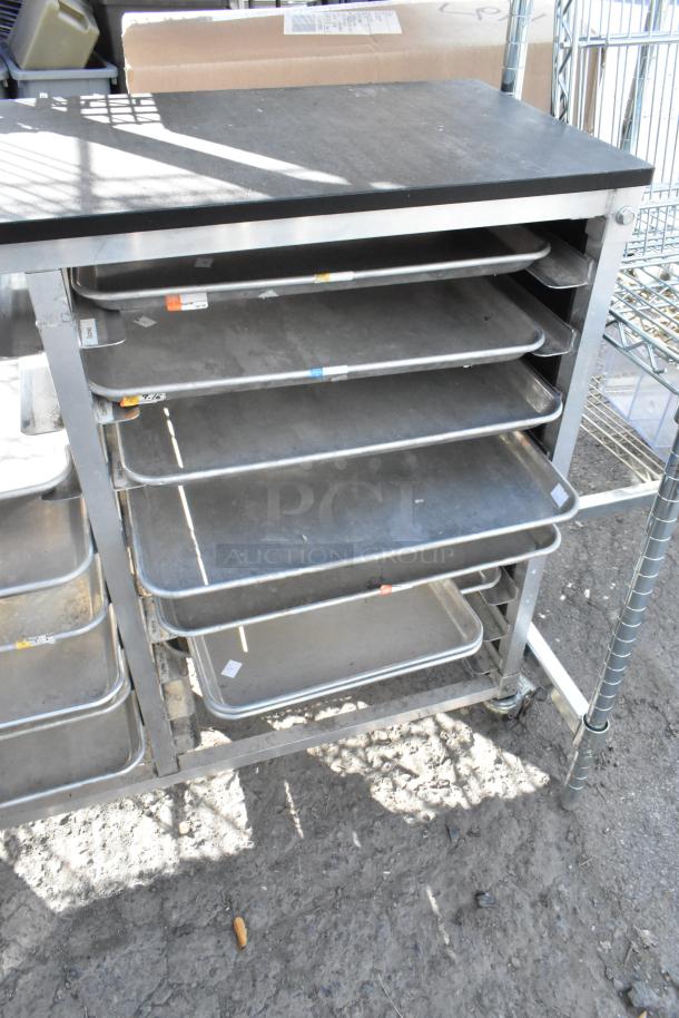 Metal cart with multiple metal baking pans, in used condition. Sturdy construction with visible wear. Ideal for baking needs.
