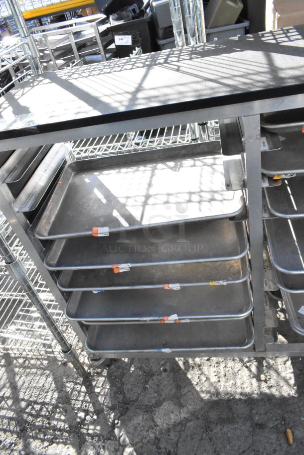 Metal cart with multiple metal baking pans on shelves. Pans have assorted labels, indicating sizes. Good condition.