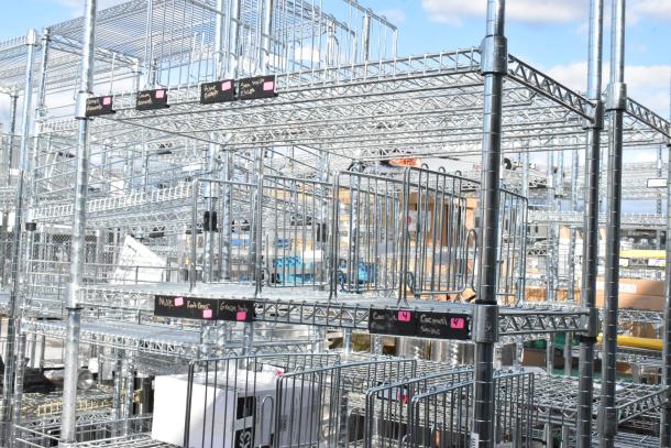 Chrome finish 6-tier wire shelving unit, undismantled. Features grid shelves with black labels for organization. Buyer must dismantle.