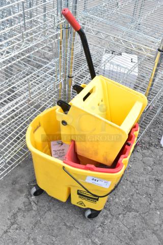 Yellow poly mop bucket with wringing attachment, Rubbermaid WaveBrake, on commercial casters, used condition, label visible.