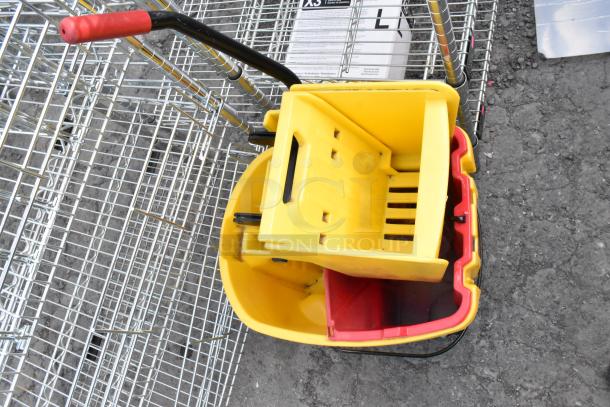 Yellow poly mop bucket with wringing attachment on commercial casters; used condition, suitable for cleaning tasks.