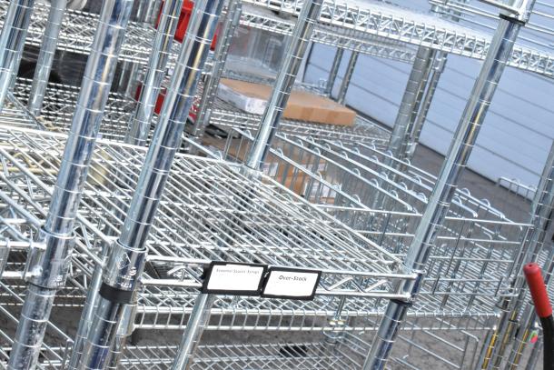 Chrome finish 6-tier wire shelving unit, in good condition. Buyer to dismantle. Tags read "Seasonal Sauces: Syrups," "Over-Stock."