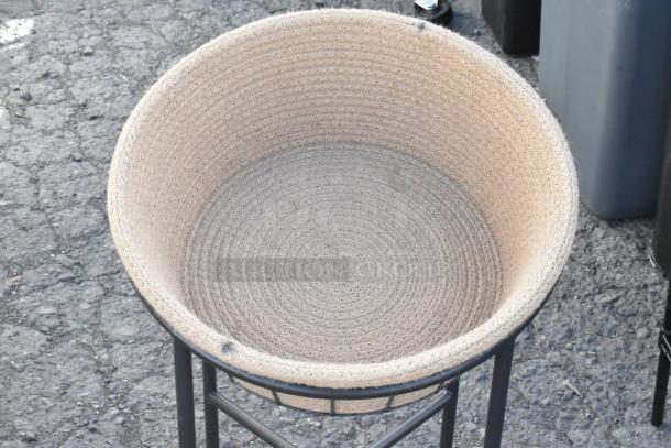 Beige braided basket in black metal stand, part of a set with folding chair, cart, and wire shelving unit. Appears intact.