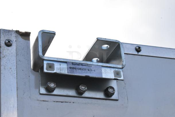 Metal swinging kitchen door hinge close-up, showing serial number "C000120227-3-1-1", sturdy metal construction, slightly worn.