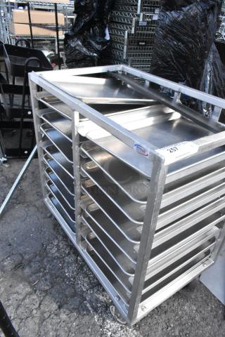 Metal commercial double pan transport rack with metal baking pans, Winholt brand. Features commercial casters, in used condition.