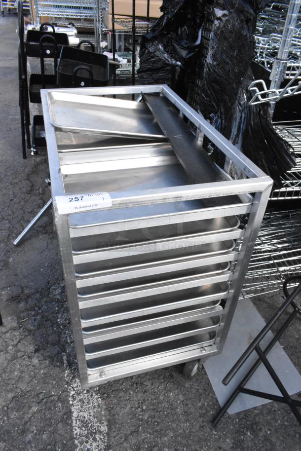 Metal commercial double pan transport rack with multiple metal baking pans, on sturdy commercial casters. Marked "257."