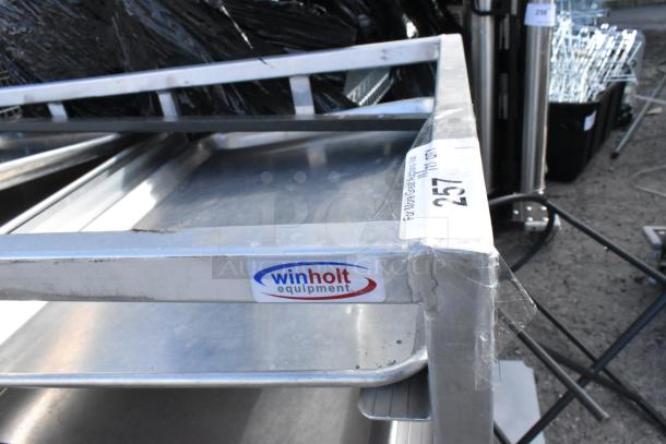 Metal commercial double pan transport rack on casters with metal baking pans. Winholt equipment label visible.