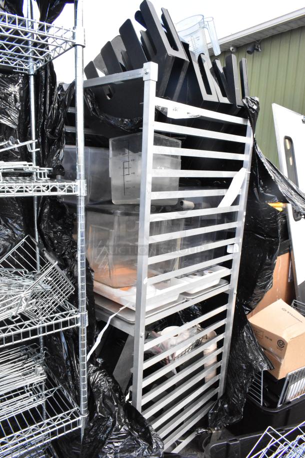 Metal commercial pan transport rack on casters filled with plastic containers and kitchen items. Suitable for storage.