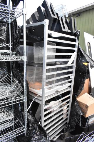 Metal commercial pan transport rack on casters filled with plastic containers and kitchen items. Suitable for storage.