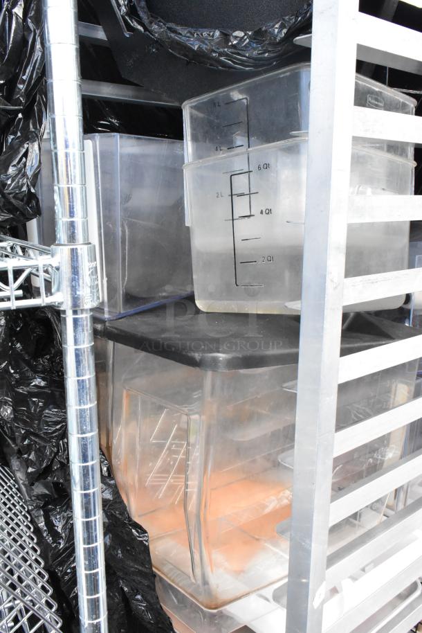 Metal commercial pan transport rack with contents on commercial casters, includes clear storage containers with measurement markings.