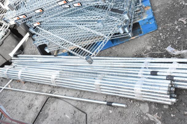 Lot of chrome finish wire shelves and poles on a pallet. Includes various sizes. Ideal for storage solutions.