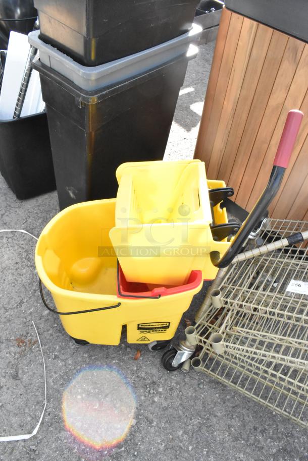 Yellow poly mop bucket with wringing attachment and commercial casters, branded Rubbermaid, in used condition.