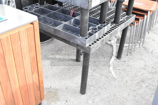 Four black poly tables with grid tops, stackable design, and sturdy legs. Used condition, ideal for warehouse use.