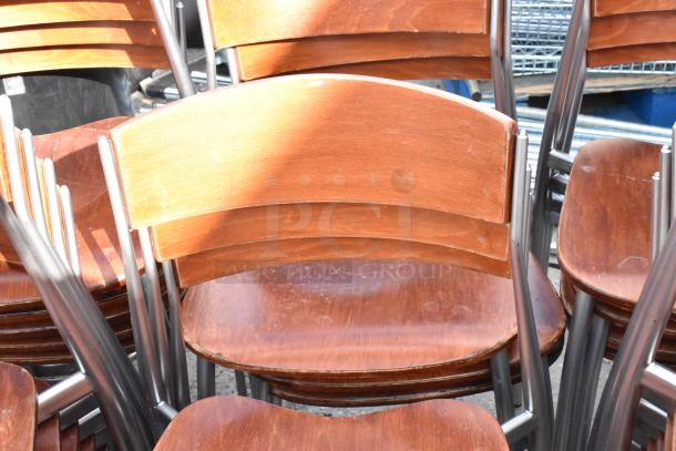 Set of 25 wooden dining chairs with chrome finish frame. Slight wear visible, sturdy construction, ideal for bulk purchase.