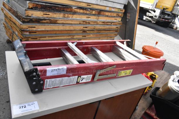 Werner A Frame Ladder, red, folded, visible safety labels and auction tags. Appears in used condition, resting on a cabinet.