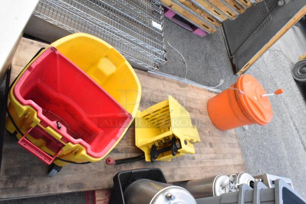 Lot of assorted items including gray Slim Jim trash cans, kegs, yellow mop bucket, and an orange container on a wooden surface.