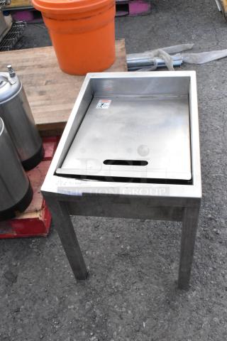 Metal bin on legs with a flat lid, stainless steel finish, visible warning label, and slight surface wear.