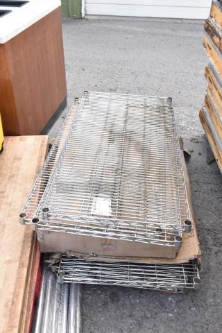 Lot of chrome finish wire shelves, stacked and labeled, show signs of wear, ideal for storage solutions.
