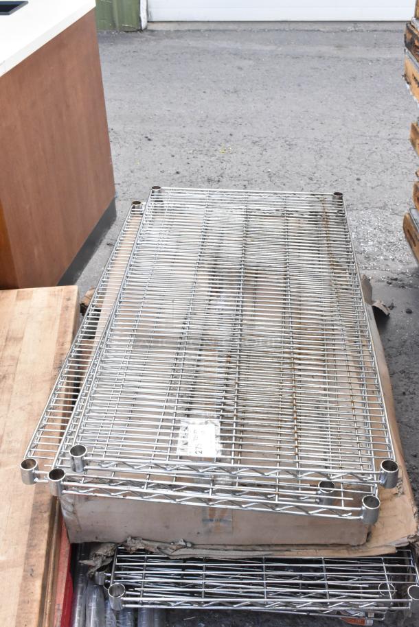 Lot of chrome finish wire shelves on a wooden pallet. Shelves appear unused with minor wear. Label reads "Made in China."