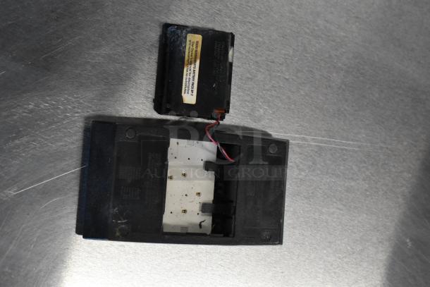 Open black electronic calculator case with visible wiring, missing battery. Surface wear noted. Set includes plates and more.