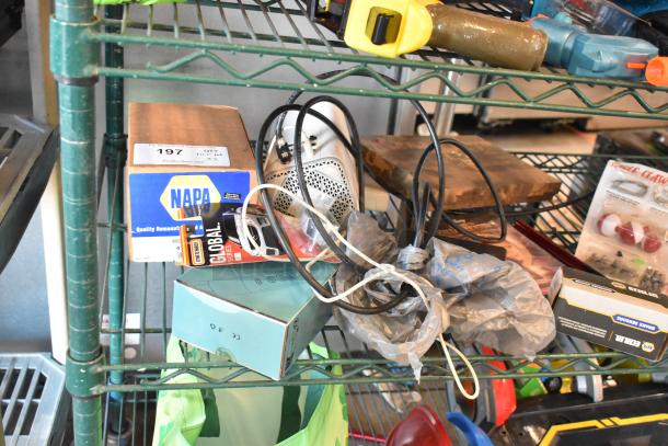 Two-tier shelf with various items including a box with "NAPA" label, fishing lures, windchimes, cables, and a Nintendo Switch controller holder.