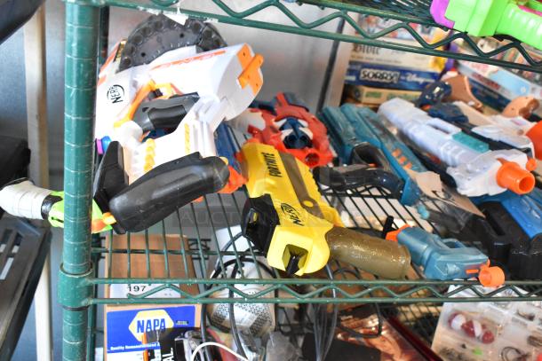 Two-tier shelf with assorted toy Nerf guns. Includes various models, some marked "Nerf" and "Fortnite." Items appear used.